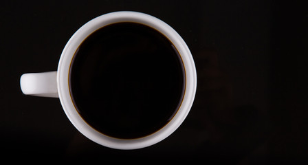 Coffee in a white mug over black background