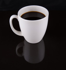 Coffee in a white mug over black background