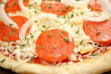 Close-Up of a Raw Pepperoni Pizza with Onions