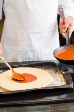 Mid section of a male chef preparing pizza