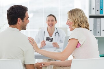 Fototapeta premium Expectant couple with doctor in clinic