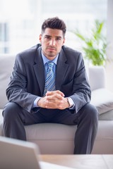 Smiling businessman sitting on the sofa looking at camera