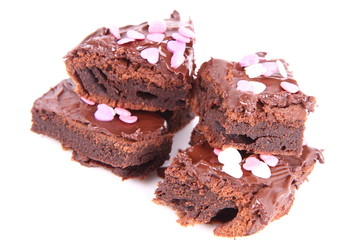 Slices of a brownie covered with chocolate and decorated with sugar hearts