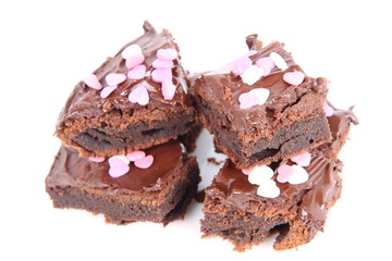 Slices of a brownie covered with chocolate and decorated with sugar hearts