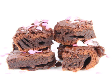 Slices of a brownie covered with chocolate and decorated with sugar hearts