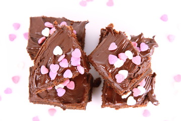 Slices of a brownie covered with chocolate and decorated with sugar hearts