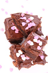 Slices of a brownie covered with chocolate and decorated with sugar hearts