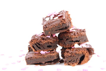 Slices of a brownie covered with chocolate and decorated with sugar hearts