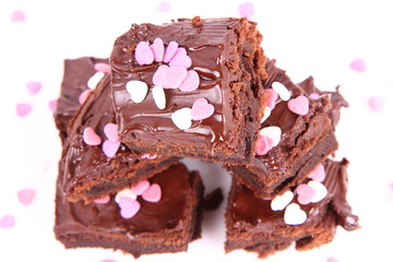 Slices of a brownie covered with chocolate and decorated with sugar hearts