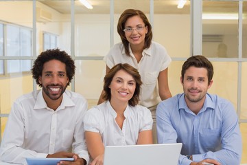 Smiling business people using laptop at office