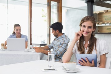 Smiling woman using digital tablet in coffee shop