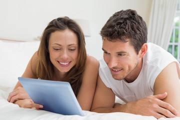 Fototapeta premium Couple using digital tablet in bed