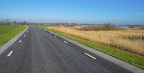 Road on a dike along a river in winter