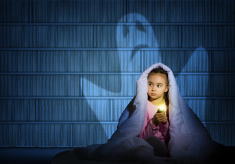 girl under the covers with a flashlight