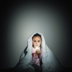girl under the covers with a flashlight