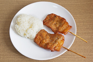 Grilled pork barbecue with sticky rice in a white dish
