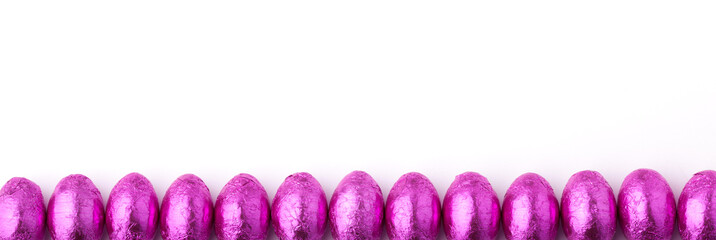 Obraz premium Row of mini chocolate eggs wrapped in pink foil