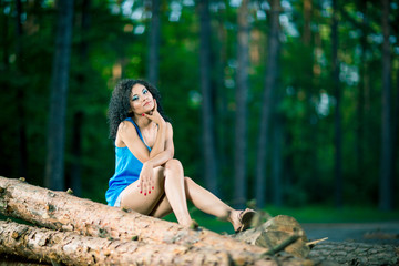 Beautiful Young Woman sitting on log posing