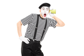 Male mime artist listening through wall with a cup