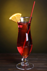 Glass of cocktail on table on dark yellow background