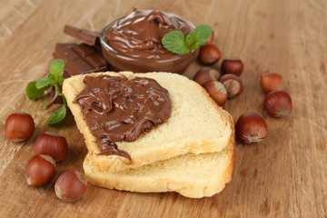 Bread with sweet chocolate hazelnut spread on wooden background