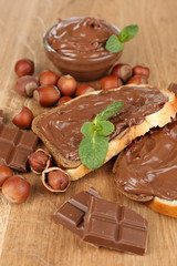 Bread with sweet chocolate hazelnut spread on wooden background
