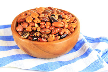 Raw beans in bowl on color napkin, isolated on white