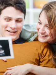 Beautiful couple watching with emotion ultrasound pictures of th