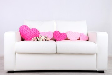 Pink hearts shaped pillow and  flowers on white sofa
