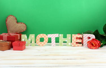 Mother- lettering of handmade paper letters on green background