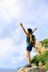 Fototapeta premium cheering woman hiker open arms at mountain peak