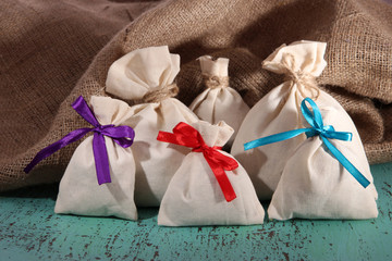 Sacks on color wooden table, on sackcloth background
