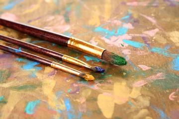 Obraz premium Many brushes in paints on multicolor wooden background