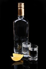 Bottle of vodka and lemon slice isolated on black