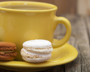 colorful macaroon with a cup of coffee on old wooden background
