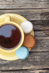 colorful macaroon with a cup of coffee on old wooden background