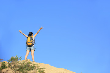 cheering woman hiker open arms at mountain peak