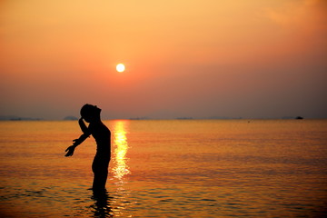 woman open arms sunrise/sunset sea