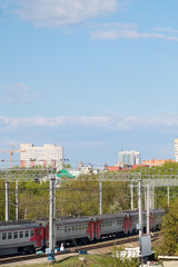 Passenger train at railways among green tees at summer day