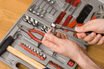 Hands holding ratchet and head over toolbox