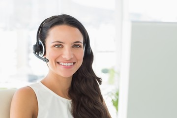 Happy call centre agent sitting at her desk