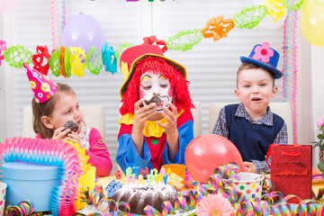 Obraz na płótnie Canvas children giving gifts on birthday party with clown