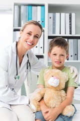 Friendly doctor with boy holding teddy bear