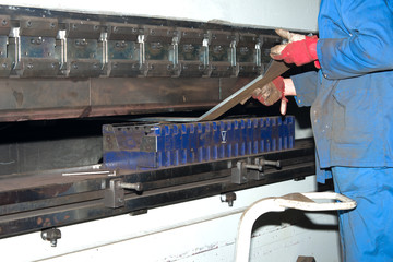 worker operating metal press machine at workshop