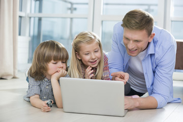 Happy father showing something to children on laptop at home