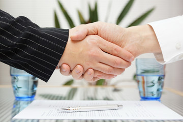businessman and businesswoman shaking hands over signed contract
