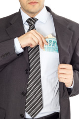 A businessman in a suit putting brazilian money in his pocket