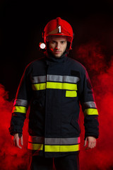 Fireman standing against red smoke.