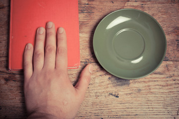 Hand with book and saucer