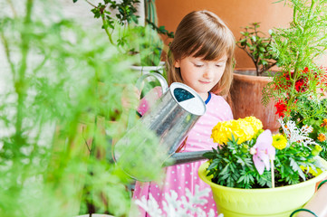 Adorable little girl watering flowers
